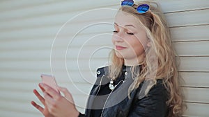 Fashionable young and beautiful girl with a smartphone in hands. The girl is looking at the phone screen. Against a