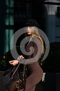 Fashionable young brunette woman wearing Solid Long Sleeve Bodycon One Piece Jumpsuits posing with a leather brown