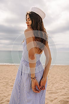 Fashionable young caucasian woman resting on coast in sunny weather on background of sea.