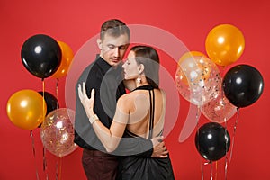 Fashionable young couple in black clothes celebrating birthday holiday party on bright red background air