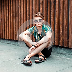 Fashionable young guy with sunglasses in a shirt and shorts