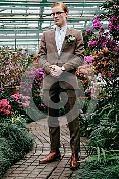 fashionable young man with red hair in suit and eyeglasses standing