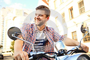 Fashionable young man riding a vintage scooter in street