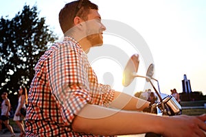 Fashionable young man riding a vintage scooter in street