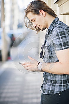Fashionable young man using a phone outdoors