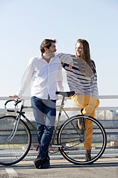 Fashionable young man and woman posing with bicycle outdoors