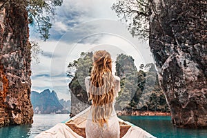 Fashionable young model in boho style dress on boat at the lake