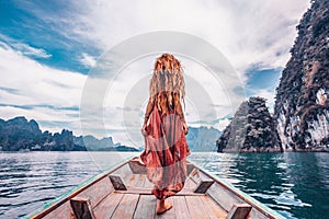 Fashionable young model in boho style dress on boat at the lake