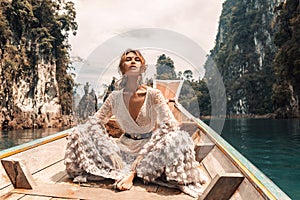 Fashionable young model in elegant dress on boat at the lake