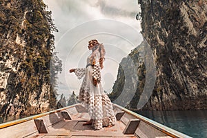 Fashionable young model in elegant dress on boat at the lake