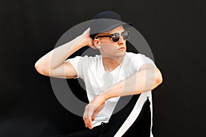 Fashionable young model of a man with sunglasses in a black cap