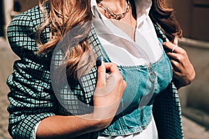 Fashionable young woman with blond hair dressed in white blouse and denim top so checkered coat posing.