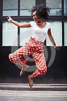 Fashionable young woman jumps up and laughs, full length photo