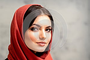 The fashionable young woman. Portrait of the beautiful female model with long hair and makeup in a red scarf. Beauty