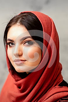 The fashionable young woman. Portrait of the beautiful female model with long hair and makeup in a red scarf. Beauty