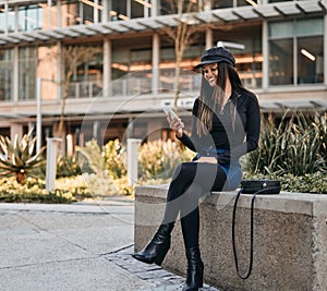 Fashionable young woman sitting with sling bag looking at her mo