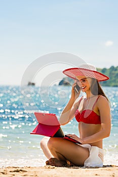 Fashionable young woman talking on mobile phone on the beach