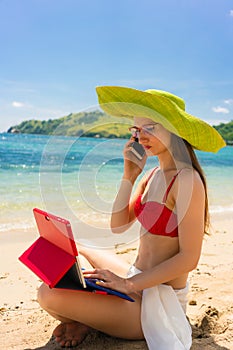 Fashionable young woman talking on mobile phone on the beach