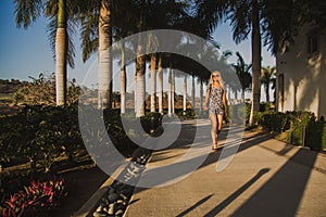 Fashionable young woman walking through Mexico with shadows of palm trees