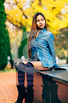 Fashionable young woman wearing blue jeans jacket with the high hills and long stripe knee socks. autumn fashion style
