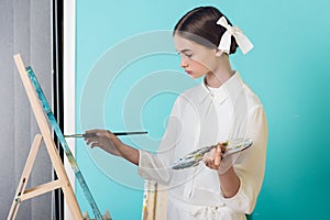 fashionable youth artist painting on easel with brush and palette