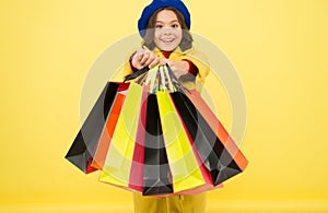 Fashionista adore shopping. Obsessed with shopping. Girl cute kid hold shopping bags on yellow background. Mid season