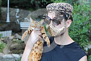 Fashionista holding a cat while wearing golden mask