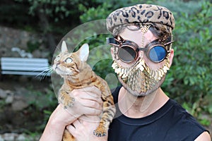 Fashionista holding a leopard cat while wearing golden mask