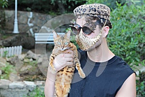 Fashionista holding a leopard cat while wearing golden mask