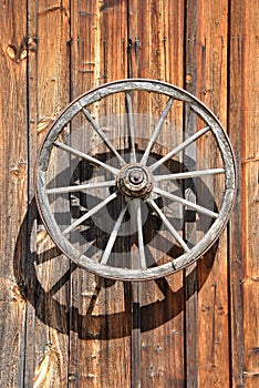 Fassade of an old, wooden Cottage with Cartwheel at Sunlight, close up