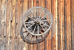Fassade of an old, wooden Cottage with Cartwheel at Sunlight, close up