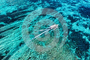 Fast boat at the sea in Bali, Indonesia. Aerial view of luxury floating boat on transparent turquoise water at sunny day. Seascape
