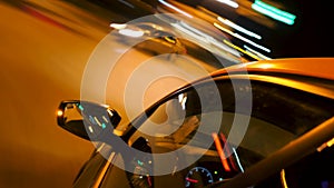 Fast car driving through night city. Stock footage. Timelapse of driving car around city with lights at night. Close-up