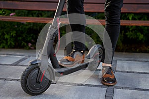 Fast and convenient. Close up shot of elegant, stylish middle aged business man standing with his electrical scooter