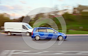 Fast driving blue car on the road with motion blur