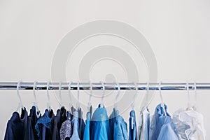 Fast fashion, Sustainable fashion, minimalist wardrobe. Variety of female blue clothing on hanging on white background