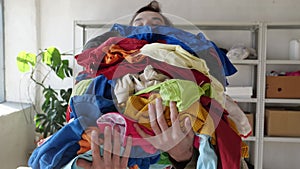 Fast Fashion and Textile Waste. A large pile of old clothes in the hands of a young man. Waste is at the heart of