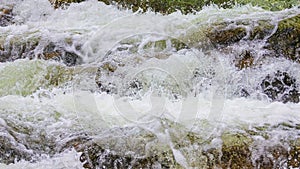 Fast flowing mountain river. Water texture with foam_