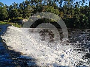 Fast flowing, turbulent water cascading over dam on Ave River in Portugal