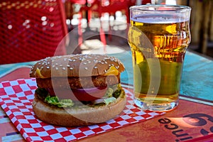 Fast food in bar served outdoor in sunny day, vegetarian hamburber and glass of cold beer