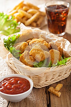 Fast food chicken nuggets with ketchup, french fries, cola