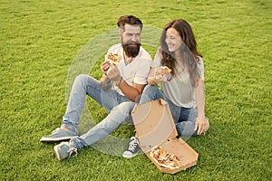 Fast food delivery. Bearded man and woman enjoy cheesy pizza. Couple in love dating outdoors with pizza. Hungry students
