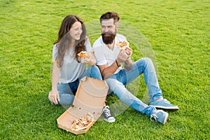 Fast food delivery. Bearded man and woman enjoy cheesy pizza. Couple in love dating outdoors with pizza. Hungry students