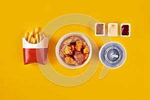 Fast food dish on yellow background. Fast food set fried chicken and french fries. Take away fast food.