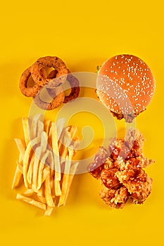 Fast food dish on yellow background. Fast food set fried chicken, meat burger and french fries. Take away fast food.