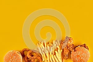 Fast food dish on yellow background. Fast food set fried chicken, meat burger and french fries. Take away fast food.