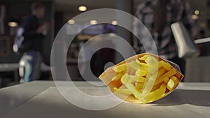 Fast food french fries potatoes lie on table inside cafe restaurant. Unhealthy lifestyle, fried and high calorie harmful