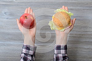 Fast food healthy unhealthy lifestyle eating decision diet fruit slimming weight loss concept. Close up photo of hands with apple