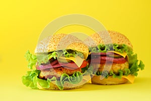 Fast food - juicy hamburger, french fries potatoes and cola drink on yellow background. Take away meal. Unhealthy diet concept