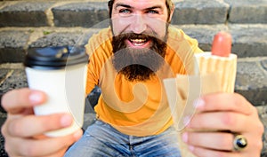 Fast food for lunch common idea. Hipster enjoy hot dog and drink paper cup beverage. Man bearded enjoy street food